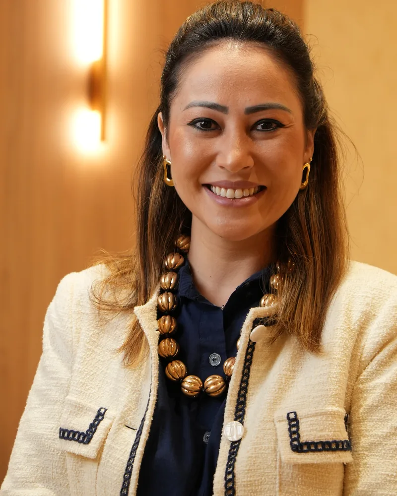 Dra. Thays Tamaributi sorrindo, de blazer creme, no Instituto Evollution